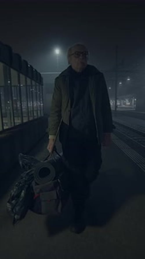 Man Walks with Bag on Dark City Street at Night