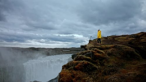 Weite Panoramaaufnahme einer gelben Reisenden, die am Rand der Klippe steht und es genießt