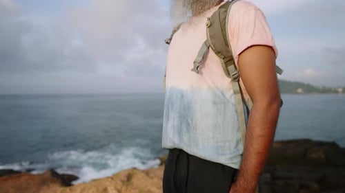 Stylish Handsome Senior Man in Tshirt Shorts Backpack with Grey Beard Sunbathes and Enjoys View of