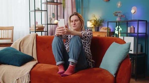 Woman Using Smartphone on Sofa in Living Room