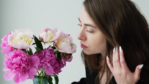 Woman Smells Pink and White Peonies