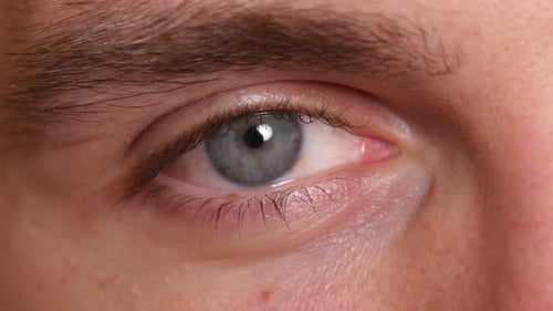 Extreme macro portrait of a young man's smiling eye in studio light