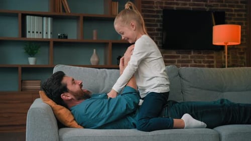 Father and Daughter Play on Couch Together