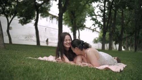 mother with her adult daughter in the park sitting each other during picnic during sunny day outdoor