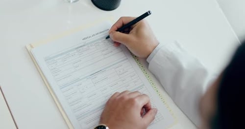 Person Filling Out Medical Form in Office