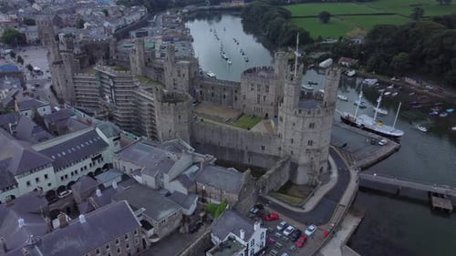 Ancient Caernarfon castle Welsh harbour town aerial view medieval waterfront landmark top down right
