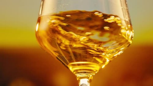 Orange or White Wine Bottle and Glass Against a Sunset in a Peaceful Vineyard Pouring of Ecological