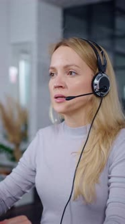 Focused Female Call Center Operator Wearing Headset Working at Computer in Modern Bright Office