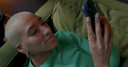 Woman Relaxing on Couch Using Smartphone