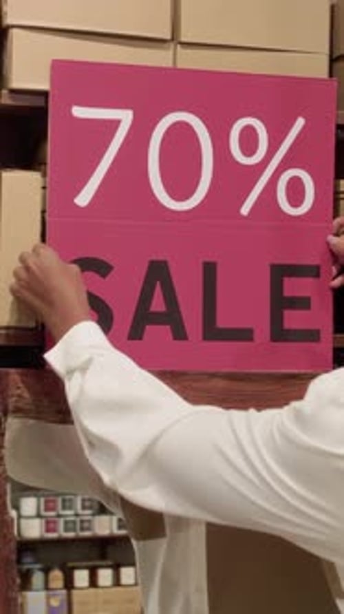 Worker Organizing Sale Sign in Department Store