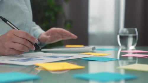 Person Analyzing Financial Data with Calculator and Graphs