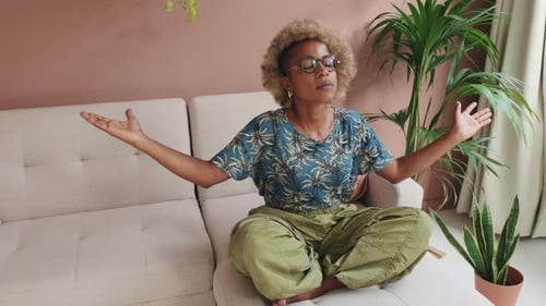Woman Meditating Cross-Legged on a Couch