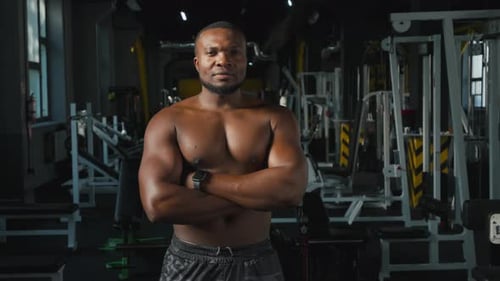 Muscular Man Smiles Confidently in Gym