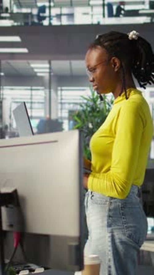 Vertikales Video: Frau steht im Büro und behebt Programmierprobleme mit Laptop