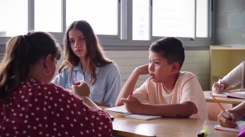 Elementary School Female Teacher Helping Her Students During Class Inside a Classroom