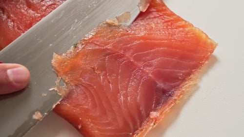 Top down view filleting a delicious smoked salmon fish with big silver knife