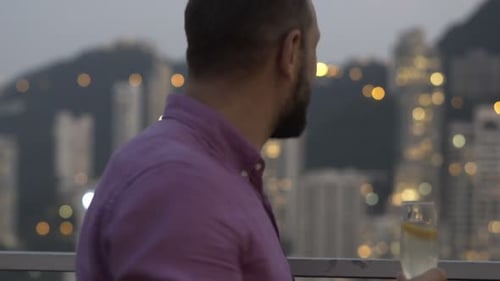 Man enjoying evening drink with city background