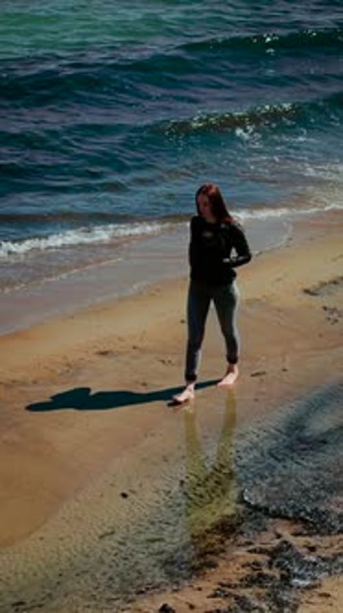 Woman Walking Along Beach with Sea Waves in Background Vertical Orientation Female Strolling