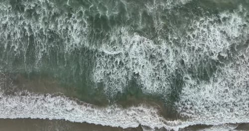Waters of the Ocean Swirl on the Beach and Scenic Coastline Aerial View Top View Drone Move