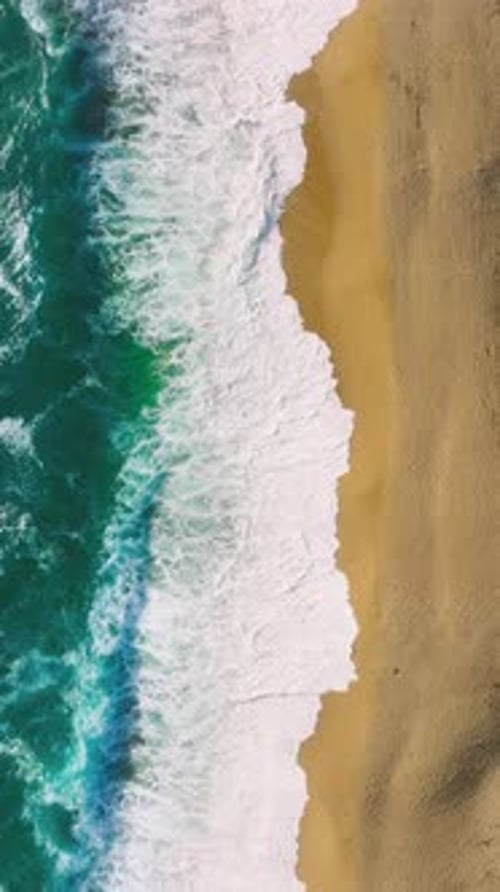 Stunning Aerial Shot of Wave Patterns Along Sandy Beach