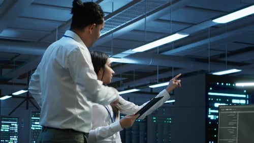 IT Professional Checks Infrastructure Performance with Tablet in Server Room