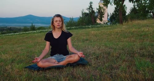 Woman practises yoga at sunrise on a meadow. Concept of fitness, healthy lifestyle