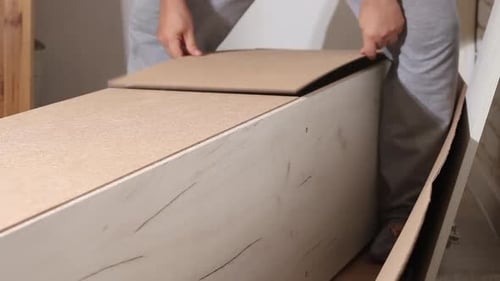 L'homme répare le mur arrière de l'armoire. À l'aide de clous. Meubles à assembler soi-même.