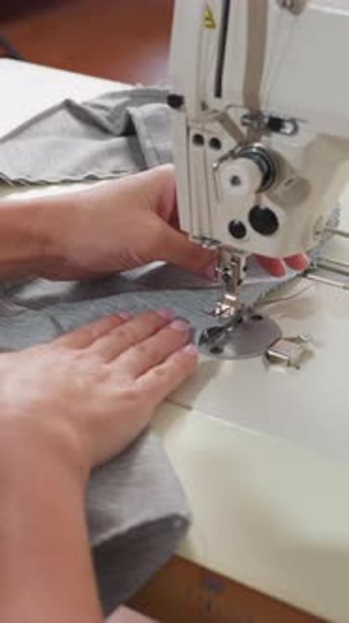 Industrial Sewing Machine Stitching Grey Fabric Caucasian Operator Guiding Cloth with Steady Hands