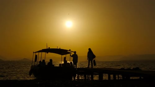 People Arriving by Boat at Sunset on Dock