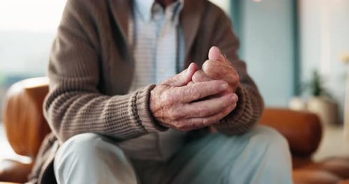 Senior Man Rubbing Aching Wrists in Living Room
