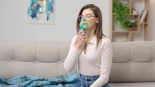 Une femme malade avec un mal de gorge fait une inhalation avec un masque sur le visage