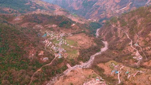 aerial view of a village situated at vibrant green valley nestled amidst rugged mountains