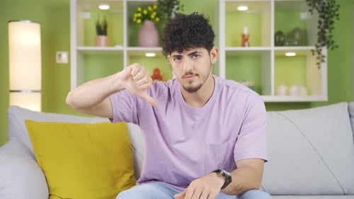 Young man making negative gesture looking at camera.