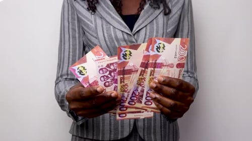 Adult Counting Stack of Ghana Cedis Currency