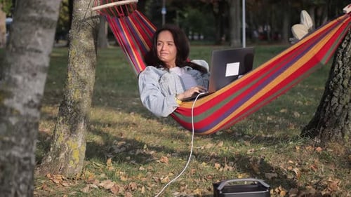 A garota está trabalhando em um laptop que está carregando de uma estação de carregamento de portal apoiada em uma rede