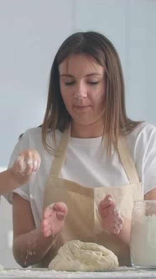 Smiling Woman in Apron Kneading Homemade Dough with Child in Bright Kitchen Sharing Floury Noses