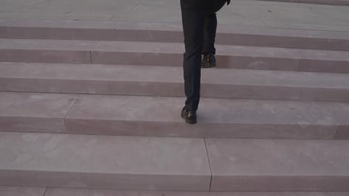 Man in Suit Runs Up Stone Stairs Outdoors