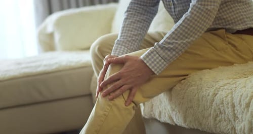 Adult Holding Sore Knee on Couch