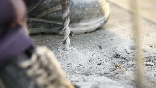 A CloseUp of a Power Drill Actively Being Used on a Concrete Surface