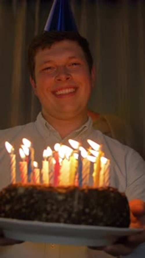 Young Adult Holds Cake with Lit Candles