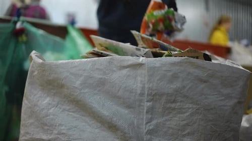 Unrecognizable People Placing Paper Garbage in Trash Can Indoors on Factory Men and Women Sorting