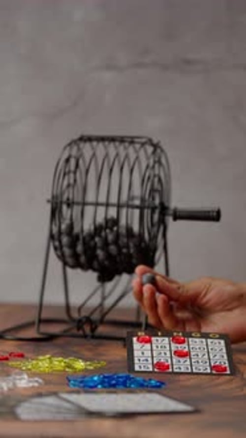 Vertical Video, The Hands Of A Latin Woman Spinning A Bingo Wheel And Taking A Bingo Ball