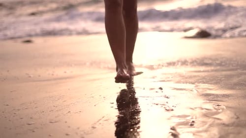 Young woman on bikini walking at the beach during sunset low angle view of feet.