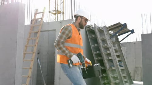 Construction Worker Walking with Drill and Toolbox