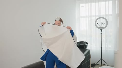 Woman in salon in blue suit with foil in hair