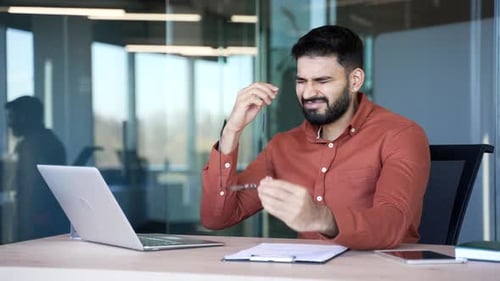 Stressed Young Adult in an Office Experiencing Headache