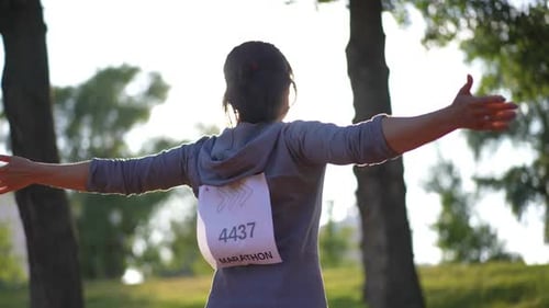 Woman Stretching Arms Before Marathon in Park