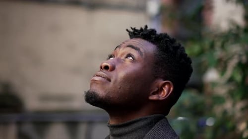 Young Man Looks Upward Outdoors in an Urban Setting