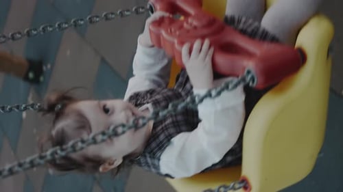 Vertical Shooting of Cute Adorable Toddler Girl Swinging on Outdoor Playground Happy Smiling Baby