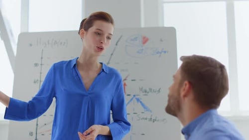 Junge Geschäftsfrau diskutiert Strategie mit männlichem Kollegen im modernen Büro